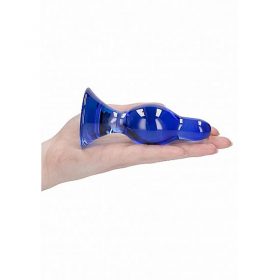 The blue glass butt plug on the palm of someones hand