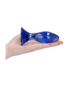 The blue glass butt plug on the flat of a persons hand