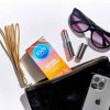 A pack of EXS Flavoured Condoms, sunglass, lipstick, whip and iphone in a handbag
