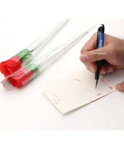 A man writing on a card with two red rose panties beside his hand